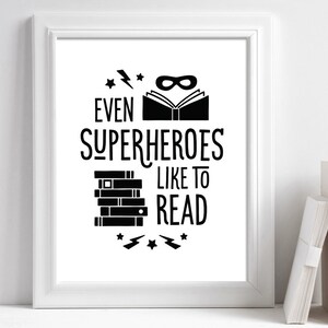 Puede incluir: Arte de pared imprimible en blanco y negro con el texto "Incluso los superh&eacute;roes les gusta leer". El dise&ntilde;o presenta una pila de libros, una m&aacute;scara de superh&eacute;roe y rayos.