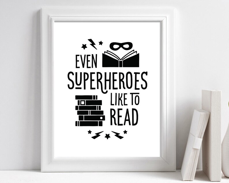 Puede incluir: Arte de pared imprimible en blanco y negro con el texto "Incluso los superh&eacute;roes les gusta leer". El dise&ntilde;o presenta una pila de libros, una m&aacute;scara de superh&eacute;roe y rayos.