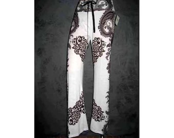 May include: White pants with a black and brown paisley print. The pants have a drawstring waist and a wide leg.