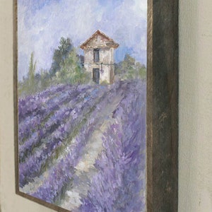May include: A framed painting of a small white house with a red roof in a field of lavender. The painting is signed "D. Cruise" in the bottom right corner.