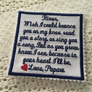 May include: A white embroidered fabric square with blue edging and a red heart. The fabric has a message that reads: "River Wish I could bounce you on my knee read. you a story, or sing you a song, But as you grow. know I see, because in your heart I'll be. Love, Papaw"