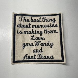 May include: A white fabric patch with black embroidered text that reads "The best thing about memories is making them. Love, gma Wendy and Aunt Diana".