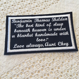 May include: A black fabric patch with white embroidered text that reads "Benjamin Thomas Sheldon "The best kind of sleep beneath heaven is under a blanket handmade with love" Love always, Aunt Chey"