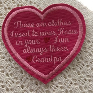 以下が含まれることがあります： 「These are clothes I used to wear, Know in your I am always there Grandpa」と刺繍されたピンクのハート型の布製パッチです。