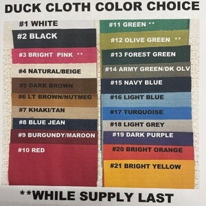 Op de afbeelding: Een kleurenkaart met 21 verschillende kleuren eendenstof. De kleuren zijn gelabeld met nummers en namen, zoals #1 Wit, #2 Zwart, #3 Felroze, #11 Groen, #12 Olijfgroen, #13 Bosgroen, #14 Legergroen/Donkergroen, #15 Marineblauw, #16 Lichtblauw, #17 Turquoise, #18 Lichtgrijs, #19 Donkerpaars, #20 Oranje, #21 Geel. De kaart bevat ook de tekst "**WHILE SUPPLY LAST**".