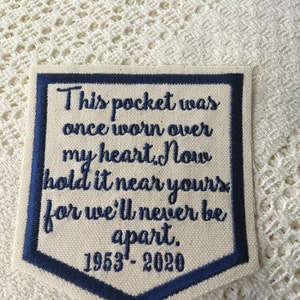May include: A blue and white embroidered patch with the text "This pocket was once worn over my heart. Now hold it near yours for we'll never be apart. 1953-2020".