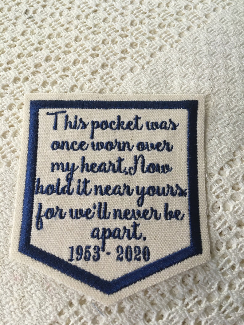 May include: A blue and white embroidered patch with the text "This pocket was once worn over my heart. Now hold it near yours for we'll never be apart. 1953-2020".