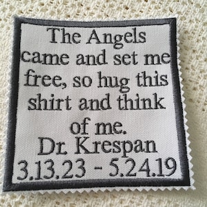 May include: A white fabric patch with black embroidered text that reads "The Angels came and set me free, so hug this shirt and think of me. Dr. Krespan 3.13.23 - 5.24.19".