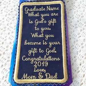 May include: A navy blue tie with a gold embroidered patch that reads "Graduate Name What you are is God's gift to you What you become is your gift to God. Congratulations 2019 Love, Mom & Dad"