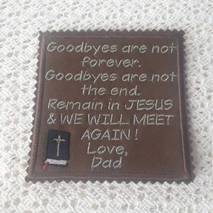 以下が含まれることがあります： 「Goodbyes are not forever. Goodbyes are not the end. Remain in JESUS & WE WILL MEET AGAIN! Love, Dad」と白く刺繍されたテキストが施された茶色の布製パッチ。左下隅には、十字架が描かれた閉じた本の小さな刺繍画像があります。