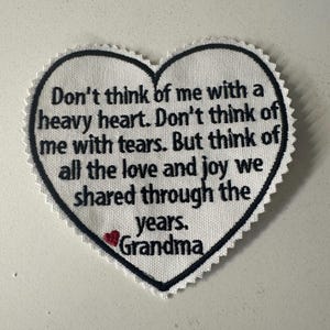 Puede incluir: Parche de tela blanco en forma de corazón con texto bordado en negro que dice "No pienses en mí con un corazón pesado. No pienses en mí con lágrimas. Pero piensa en todo el amor y la alegría que compartimos a través de los años. Abuela".