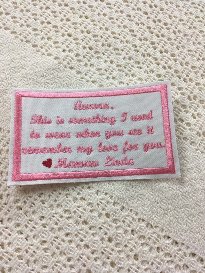 Pu&ograve; includere: Toppa ricamata rosa con il testo "Aura. This is something I used to wear when you see it remember my love for you. Mamaw Linda" e un piccolo cuore rosa.