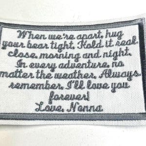 May include: A white fabric patch with a grey border and embroidered text that reads: "When we're apart, hug your bear tight. Hold it real close, morning and night. In every adventure, no matter the weather. Always remember, I'll love you forever! Love, Nonna."