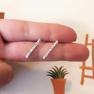 May include: A pair of silver bar earrings with clear cubic zirconia stones.