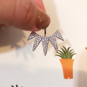May include: A silver ear cuff with a geometric design featuring multiple points covered in clear rhinestones.