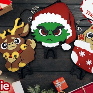May include: Festive keychains with a reindeer, a Grinch, and a cat in a stocking. The reindeer is brown with gold antlers and bells. The Grinch is green with a Santa hat. The cat is tan with holly. Keychains are included.