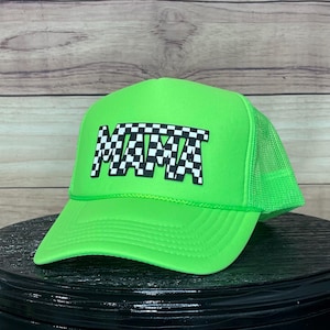 Può includere: Un cappello da camionista verde neon con un design "MAMA" a scacchi bianco e nero.
