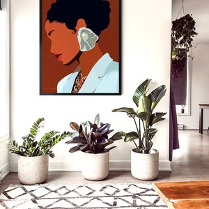 May include: A framed art print featuring a minimalist portrait of a person with dark hair and a large, pearl-like earring. The person is wearing a white blazer. The artwork hangs on a white wall above three potted plants and a patterned rug.