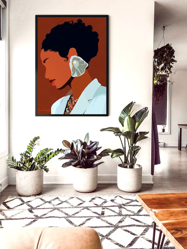 May include: A framed art print featuring a minimalist portrait of a person with dark hair and a large, pearl-like earring. The person is wearing a white blazer. The artwork hangs on a white wall above three potted plants and a patterned rug.
