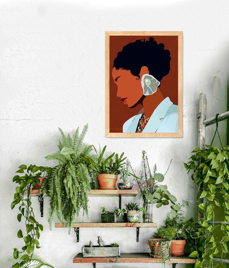 May include: A framed art print featuring a stylized portrait of a person with dark hair and a seashell earring. The artwork has a brown background and is set against a white wall with several shelves of potted plants, creating a natural, artistic aesthetic.