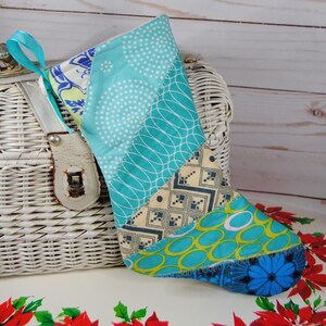 May include: A handmade Christmas stocking with a patchwork design. The stocking features various fabrics in shades of blue, teal, and cream, with patterns including polka dots, geometric shapes, and floral motifs. A teal ribbon loop is attached for hanging.