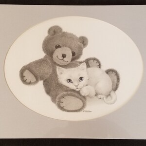 May include: A black and white drawing of a teddy bear with a white kitten nestled in its arms. The drawing is framed in a light gray oval.