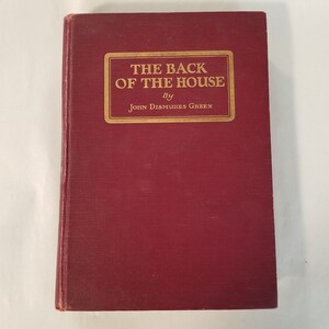 May include: A burgundy hardback book with gold lettering on the spine and front cover. The title is "The Back of the House" by John Dismukes Green.