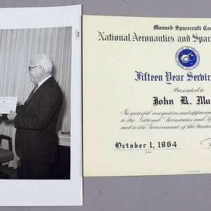 Pu&ograve; includere: Fotografia in bianco e nero di due uomini, uno dei quali consegna un certificato all'altro. Il certificato &egrave; un "Fifteen Year Service Award" della National Aeronautics and Space Administration, datato 1 ottobre 1964.