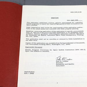 Pu&ograve; includere: Libro aperto con copertina rossa e pagine bianche. Il testo include il titolo "PREFACE" e la data "Aprile 1969". Il documento &egrave; una pubblicazione NASA sui programmi di qualit&agrave; per i sistemi spaziali.