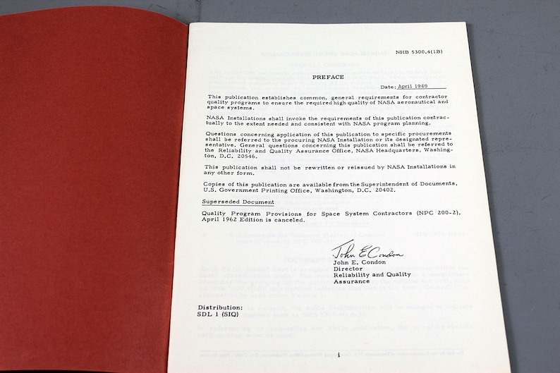 Pu&ograve; includere: Libro aperto con copertina rossa e pagine bianche. Il testo include il titolo "PREFACE" e la data "Aprile 1969". Il documento &egrave; una pubblicazione NASA sui programmi di qualit&agrave; per i sistemi spaziali.