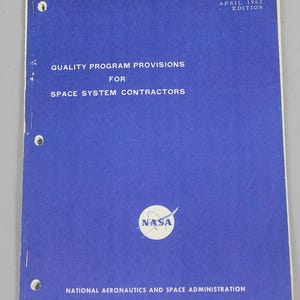 Puede incluir: Una publicación azul de la NASA titulada "Quality Program Provisions for Space System Contractors". La portada incluye el logotipo de la NASA y el texto "NASA Quality Publication NPC 200-2, April 1962 Edition."