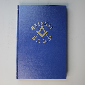 May include: A blue hardcover book with gold lettering on the front cover. The text reads MASONIC HARP, arranged in a circular pattern around a gold square and compass symbol. The book has a solid blue spine and a textured front cover surface.