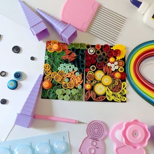 May include: A colourful assortment of paper quilling supplies, including a rainbow of paper strips, a glue bottle labelled "Blick White Glue", a set of quilling tools, and a finished quilling art piece.
