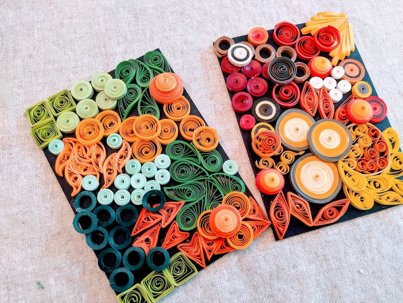 May include: Two framed pieces of paper art featuring colourful paper quilling designs. The designs are made up of circles, swirls, and other shapes in shades of green, orange, red, and yellow.
