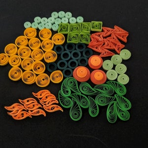 May include: A colourful assortment of paper quilling designs in green, orange, and yellow. The designs include circles, squares, swirls, and leaves.