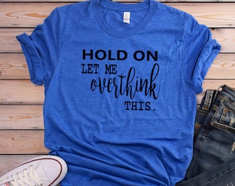 May include: A royal blue t-shirt with the text "HOLD ON LET ME overthink THIS." printed in black.
