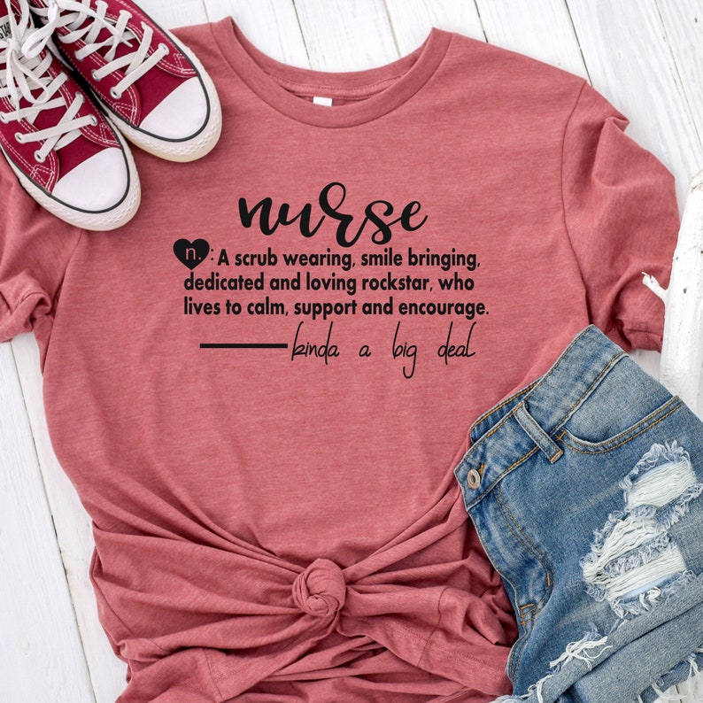Puede incluir: Una camiseta de color marr&oacute;n rojizo con un gr&aacute;fico negro que dice "nurse: A scrub wearing, smile bringing, dedicated and loving rockstar, who lives to calm, support and encourage. - kinda a big deal"
