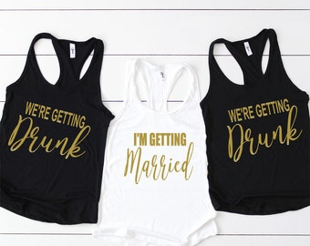 May include: Three tank tops with gold lettering. One white tank top says "I'm Getting Married". Two black tank tops say "We're Getting Drunk".