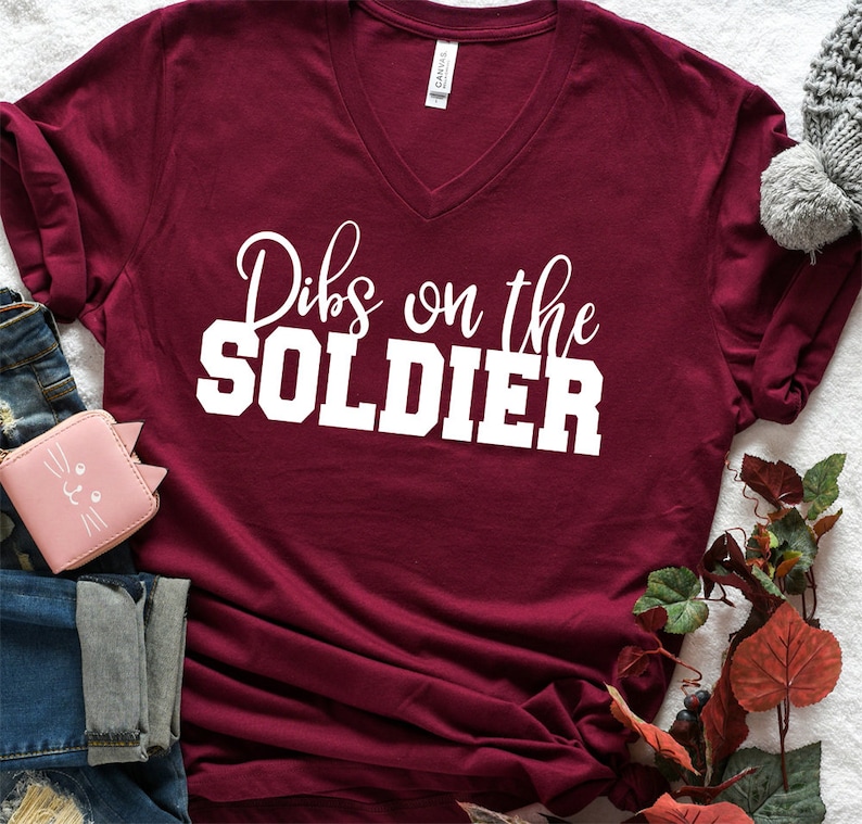 Op de afbeelding: Een bordeauxrood t-shirt met V-hals en de tekst "Dibs on the SOLDIER" in wit.