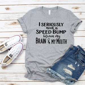 May include: Gray t-shirt with the text "I seriously need a speed bump between my brain & my mouth".