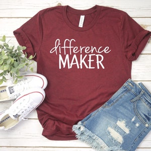 Op de afbeelding: Een maroon t-shirt met de tekst "difference maker" in witte letters.