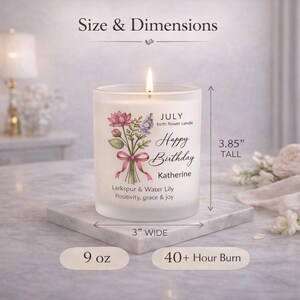 May include: A lit, white candle in a glass jar, featuring a floral design and the words "Happy Birthday Katherine." The candle is 3.85 inches tall and 3 inches wide, with a 9 oz capacity and a 40+ hour burn time.