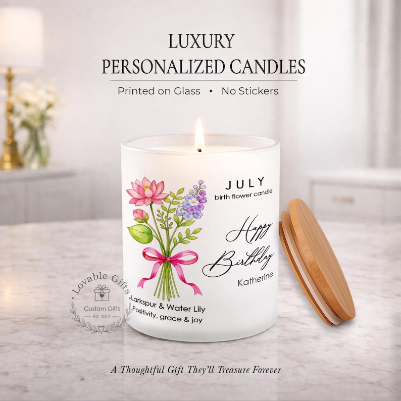 May include: A white personalized candle with a floral design and the text "Happy Birthday Katherine." The candle has a wooden lid and the text "July birth flower candle." The candle reads "Lovable Gifts Custom Gifts Est. 2017."