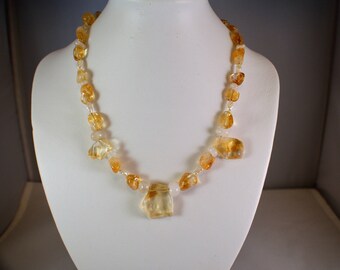 May include: A necklace made of light yellow and clear faceted gemstone beads. The necklace is on a white mannequin.