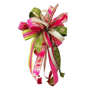 May include: A decorative bow made of multiple ribbons in vibrant shades of hot pink, lime green, and metallic gold. The ribbons feature various patterns including floral motifs, lattice designs, and solid colors with glittery gold edges.