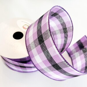 May include: A roll of purple and white plaid ribbon with black accents. The ribbon is on a white background.
