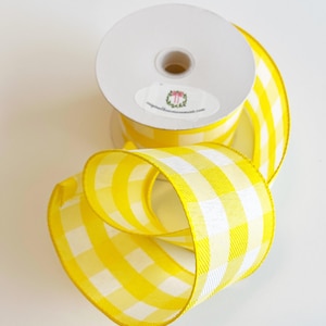 May include: A roll of yellow and white gingham ribbon. The ribbon is 2.5 inches wide and has a white background with yellow squares.