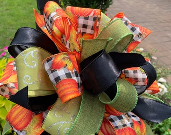Op de afbeelding: Een feestelijke herfst postbus strik met zwarte, groene en oranje linten. De linten hebben een pompoen en ruitpatroon.