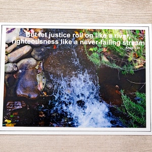 May include: A close-up photo of a small waterfall flowing over rocks. The water is clear and bubbly. The photo is framed with a white border and includes the text "But let justice roll on like a river, righteousness like a never-failing stream Amos 5:24".