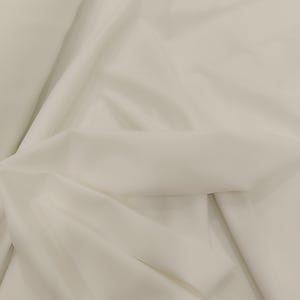 Könnte beinhalten: Nahaufnahme eines weißen Stoffes mit sanften Falten und subtilen Schatten. Der Stoff wirkt glatt und leicht, möglicherweise geeignet für Kleidung oder Vorhänge. Der Gesamteindruck ist neutral und sauber.